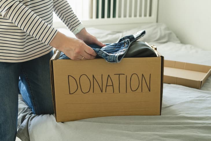 Donation concept. Young woman with donation box at home. Woman donates clothes. Lifestyle, sustainable concept