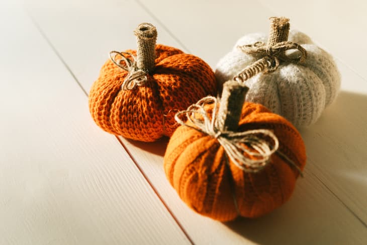 Decorative knitted pumpkins from white and orange threads. Handmade. Halloween and Thanksgiving Day zero waste concept. DIY decor. Hard shadows from sunlight