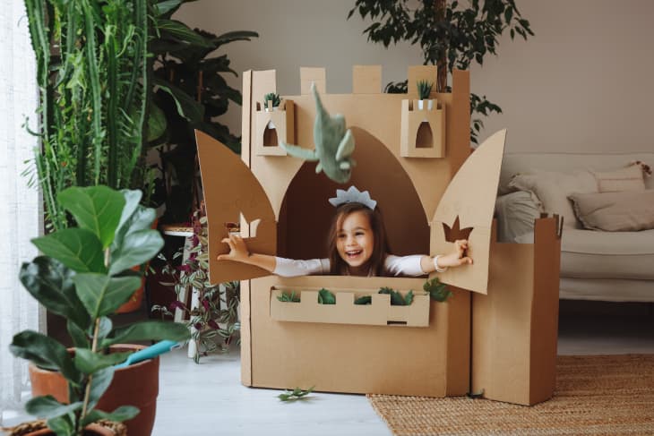 A cute little girl dressed up as a princess while playing at home in cardboard box castle