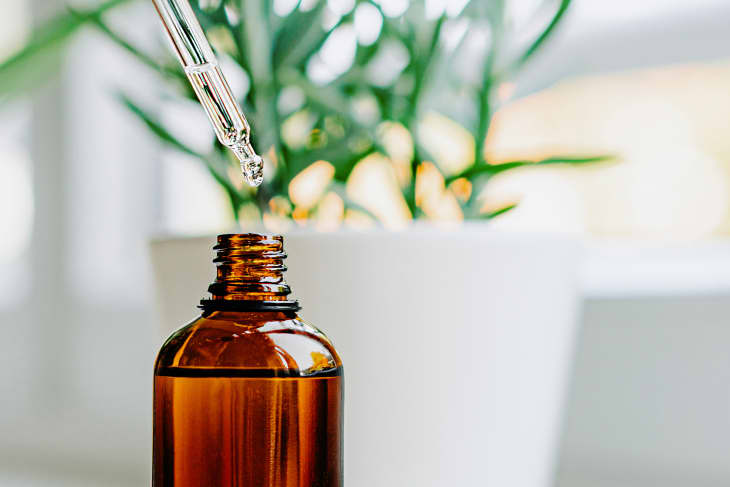 Close up of face serum pouring from a pipette into an amber glass bottle. Natural skincare and essential oil aromatherapy. Health and wellness concept.