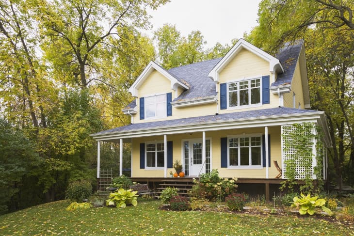 Yellow clapboard with blue and white trim cottage style home facade in autumn, Quebec, Canada.
