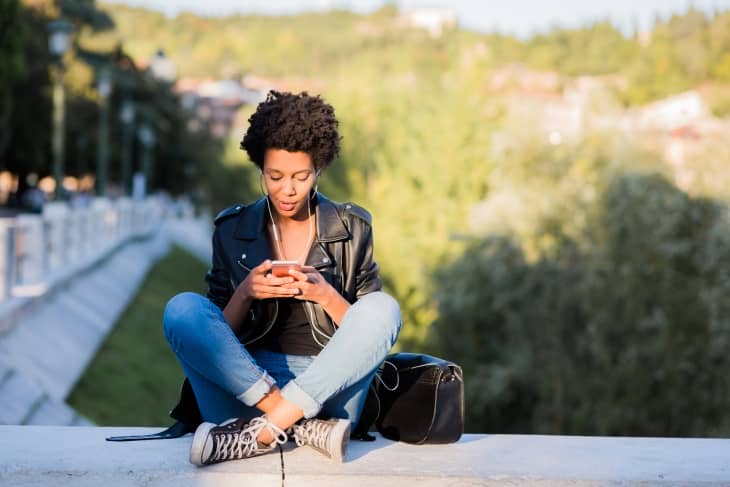 woman looking at her cellphone sitting outside