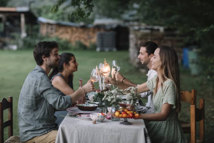 在后院的晚宴上，快乐的朋友们围坐在餐桌旁，用prosecco举杯祝酒。