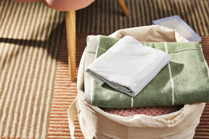 Laundry basket on living room rug with folded clothes in it
