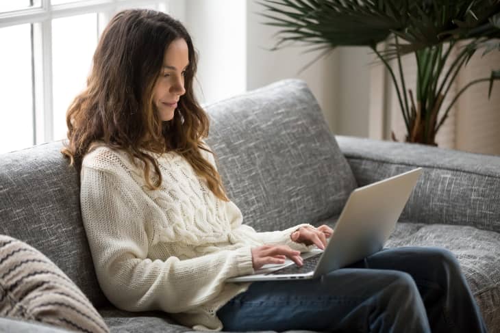 Woman sitting on sofa with laptop at home