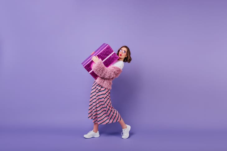 Lovable young woman in white sneakers posing with present box.