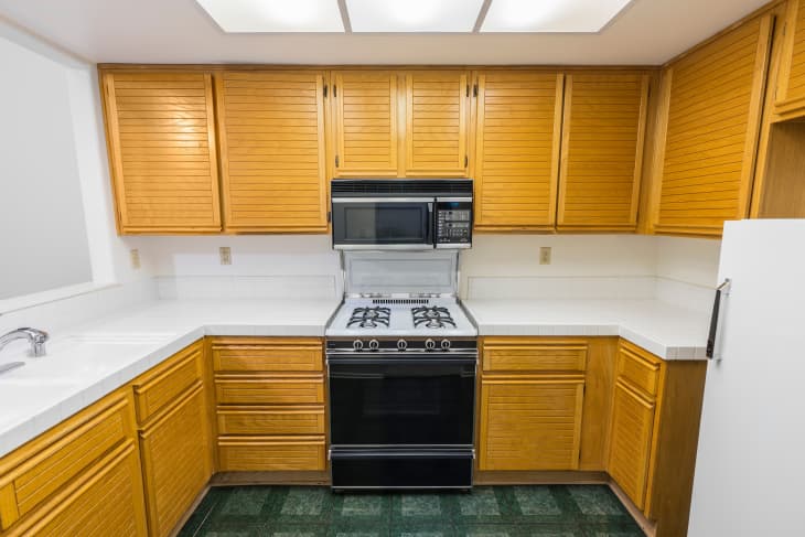Old condo kitchen with oak cabinets, tile countertops, gas stove and green flooring.  Unchanged since 1988.
