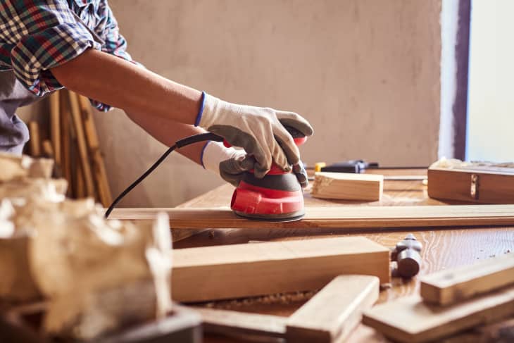 woman using sander to work with wood furniture