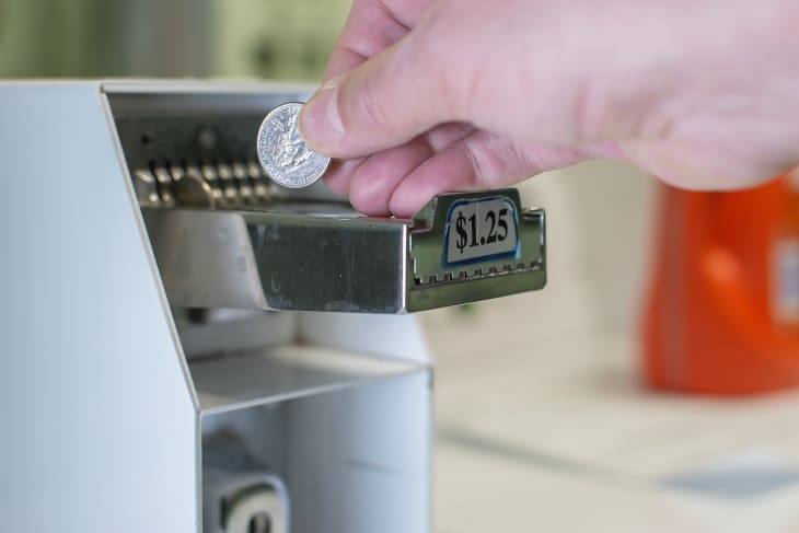 Close up from hand is adding quarters to dryer machine