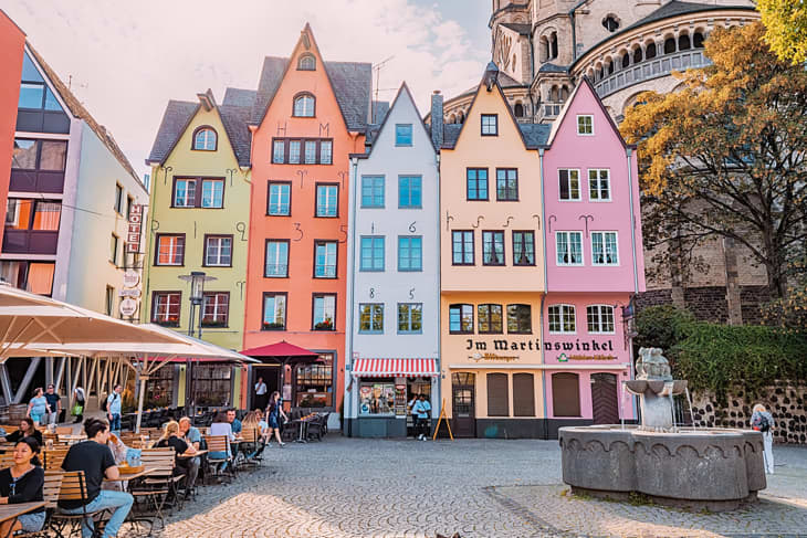Fish market square with tourists resting in cafes, colorful houses and St. Martin Church in Koln. Travel and sightseeing