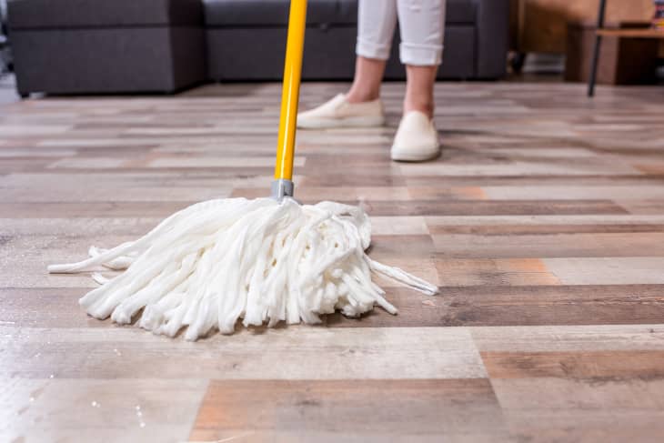 Close-up partial view of woman cleaning floor with string mop