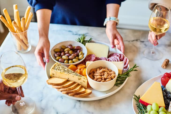 a woman placing a charcuterie board on a marble counter