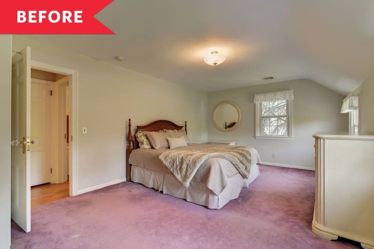 Bedroom with pink carpet, wooden bed, beige bedding, round mirror, and open door.