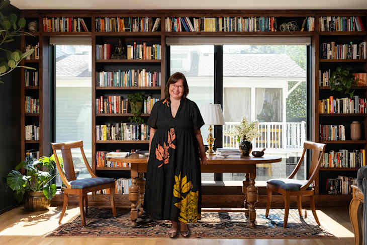 Picture of Kristin Keyes in front of her signature wall of library books in her home office