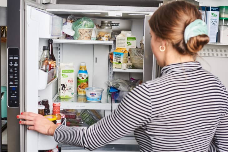 A woman opens the door of her refrigerator