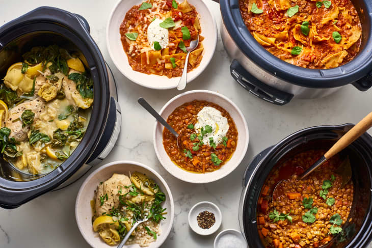 Slow cookers with various dishes including chicken with spinach and lemon, lasagna, and lentil stew garnished with herbs.
