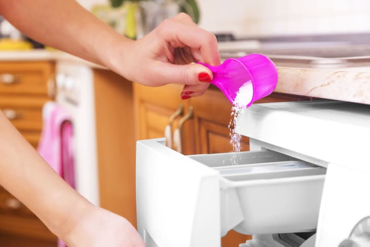 A woman adding detergent to a washing machine