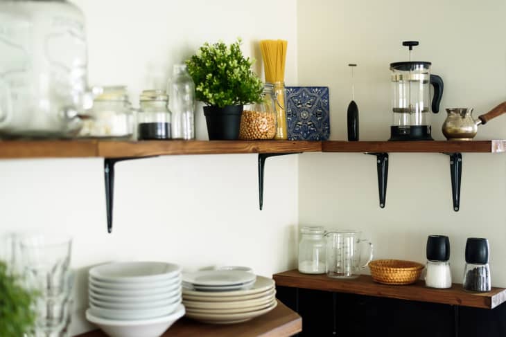 Dish and decorations on open wooden shelves in white kitchen