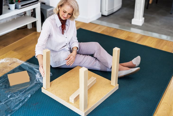 An exciting senior woman is assembling a new table as a home interior improvement.