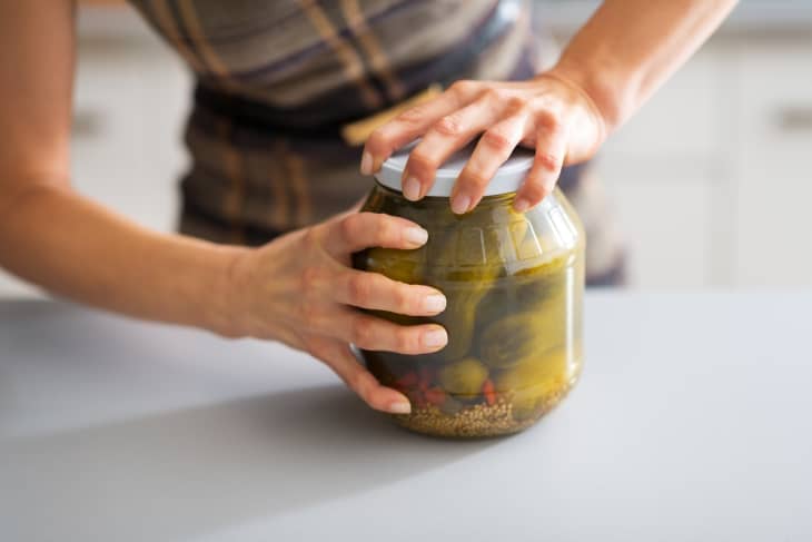 Someone opening jar of pickled cucumbers