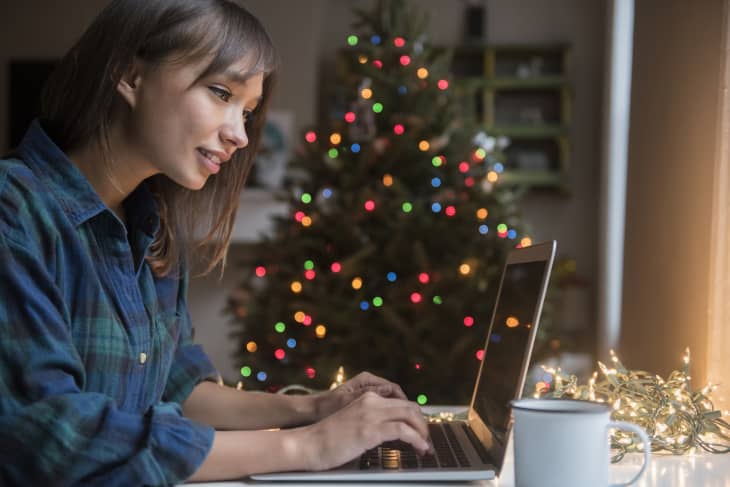 Woman using laptop near Christmas tree