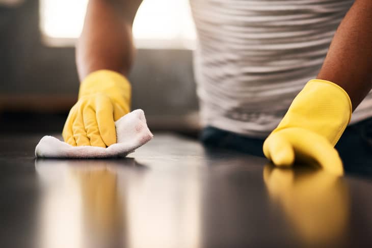 Man hands, cleaning gloves and wipe on a table with a wash cloth and housekeeping. Home, countertop and male person with disinfectant and scrub with washing in a apartment with maid and housekeeper