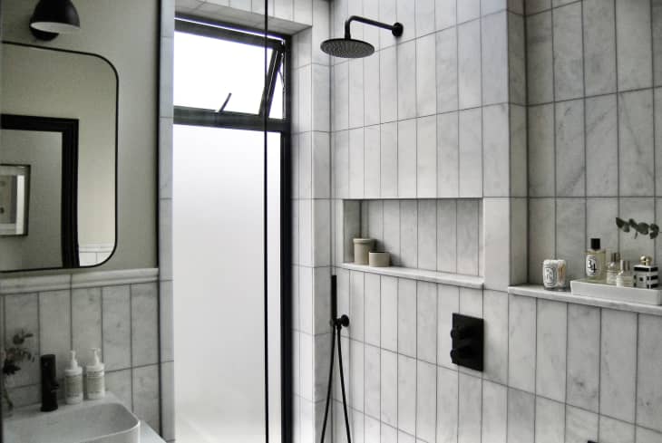 bathroom with vertical gray tiles, black hardware and accents, wet room shower