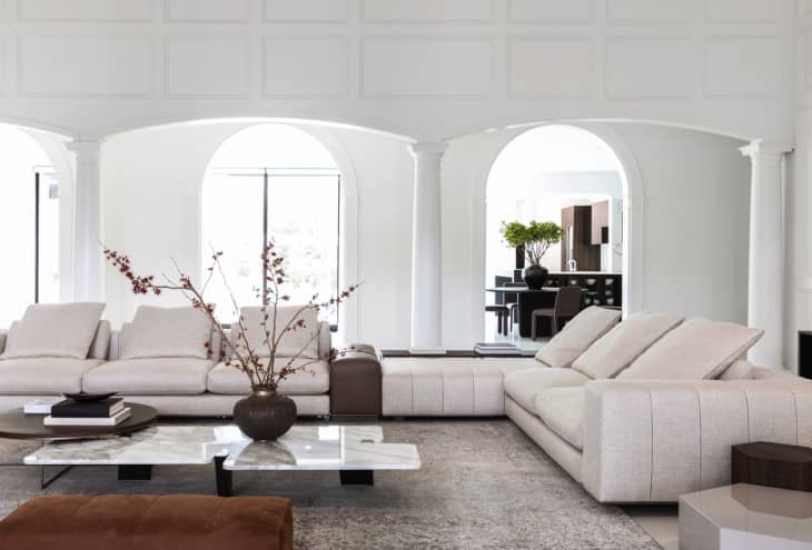 White living room with a big white sectional and pretty archways and columns