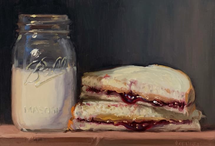 Peanut butter and jelly sandwich next to a mason jar filled with milk.