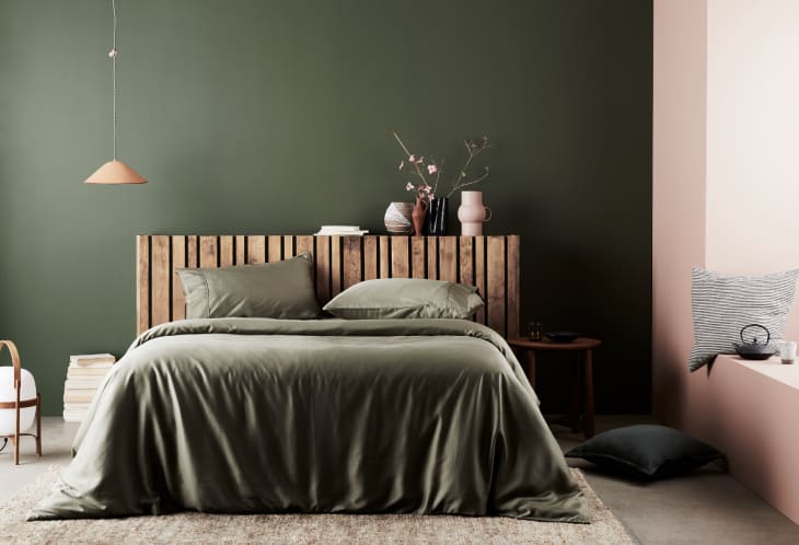 green and pink bedroom with green bedspread and wooden headboard