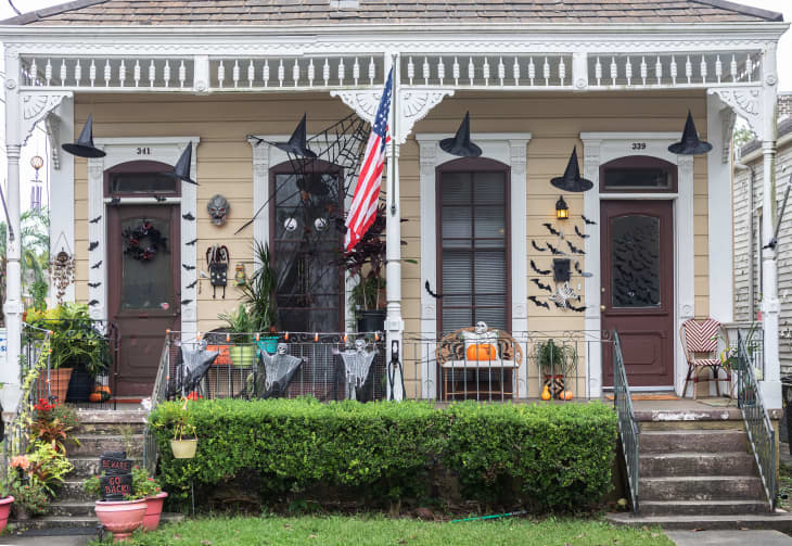 Two adjacent houses with Halloween decor, including witch hats, bats, pumpkins, and an American flag.