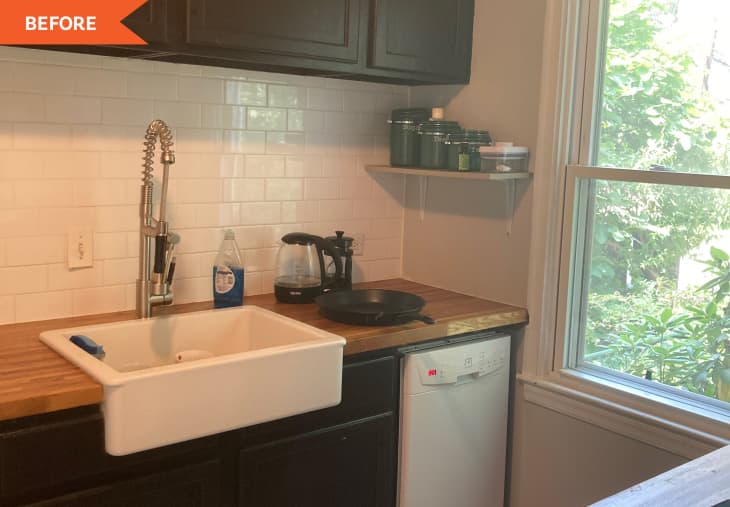 Small kitchen with farmhouse sink, wooden countertop, black cabinets, and a window overlooking greenery.