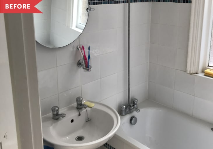 Small bathroom with round mirror, white sink, and bathtub. Two toothbrushes in a holder by the sink.