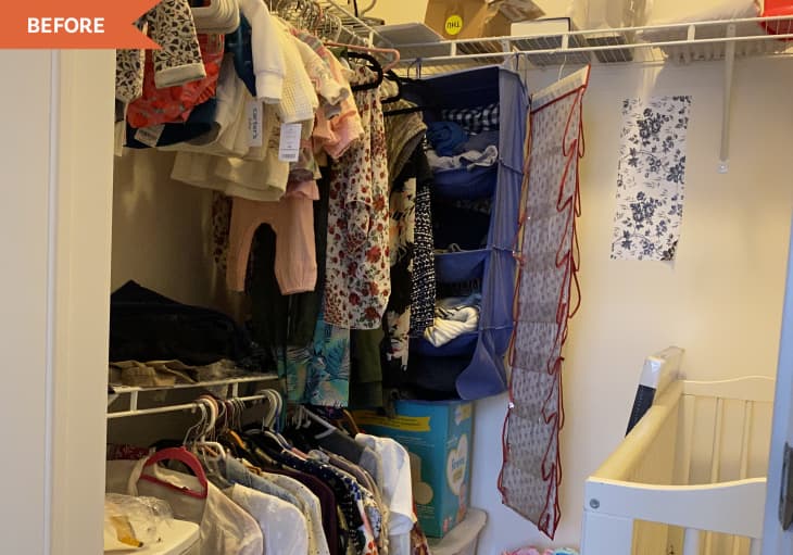 Closet with baby clothes on hangers, storage bins, and a crib.