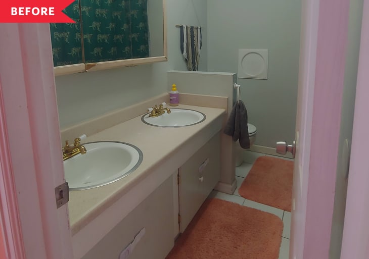 Bathroom with double sinks, gold faucets, orange rugs, and a wall tapestry.