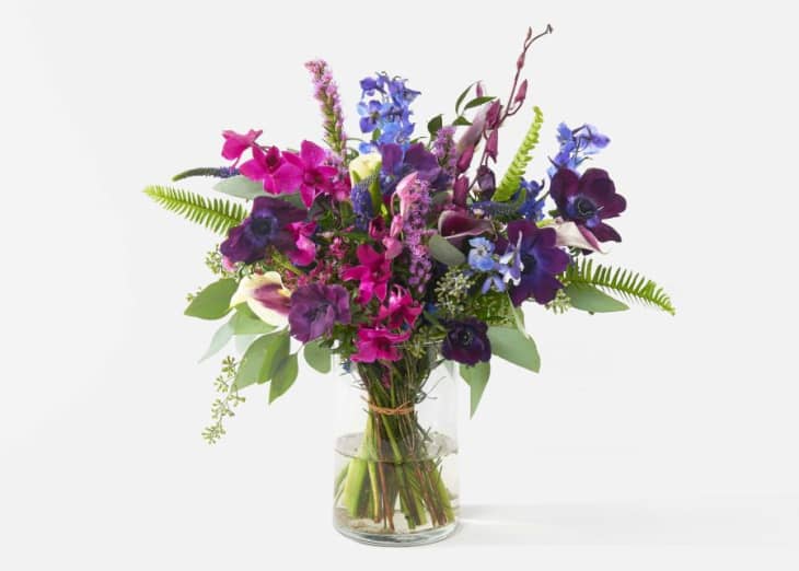 Vibrant bouquet with purple, pink, and blue flowers in a clear glass vase.