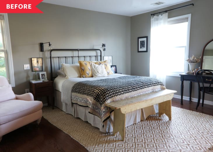 Bedroom with metal bed frame, patterned bedding, wooden bench, and a vanity table by the window.