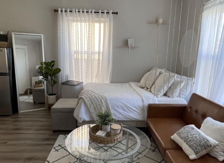 A small basket is placed on a glass coffee table in a studio apartment.