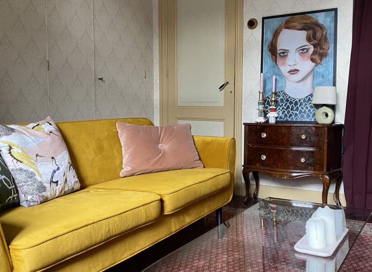 客厅有黄色沙发和大型肖像艺术品上面的古董自助餐