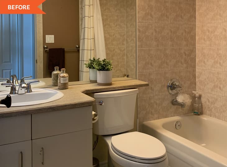 Small bathroom with beige tiles, white sink, toilet, bathtub, and potted plant on the counter.