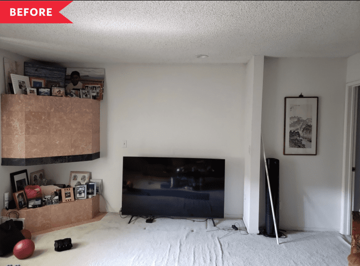 Living room with a large TV, framed art, and a corner shelf displaying family photos and decor items.