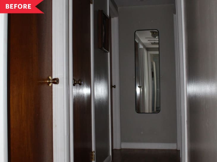 Narrow hallway with dark wooden doors and a tall mirror on the right wall.