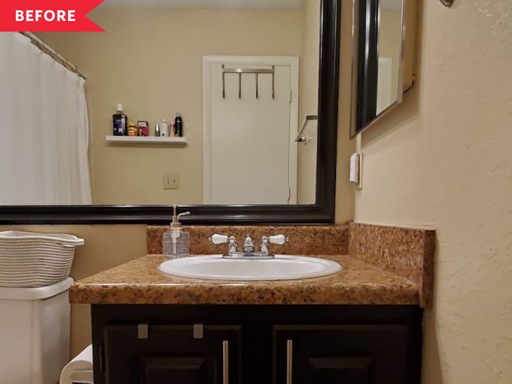Bathroom with brown granite countertop, white sink, black framed mirror, and shelf with toiletries.