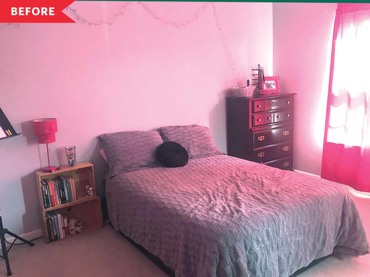 Bedroom with pink walls, gray bedding, a black pillow, wooden bookshelf, and dark dresser under string lights.