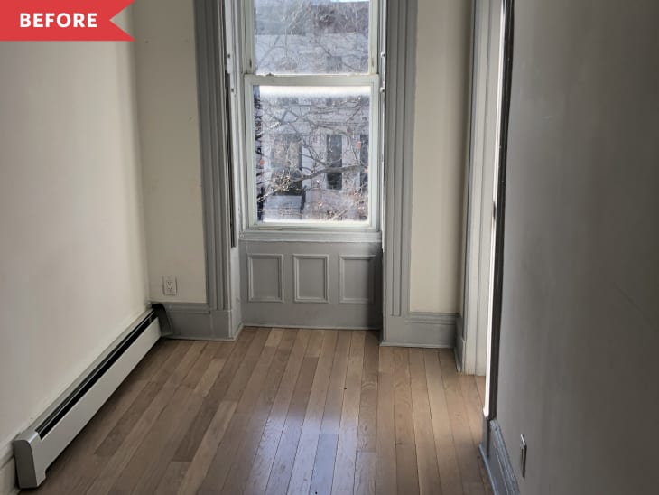 Empty room with light wood flooring, a large window with gray trim, and a baseboard heater.