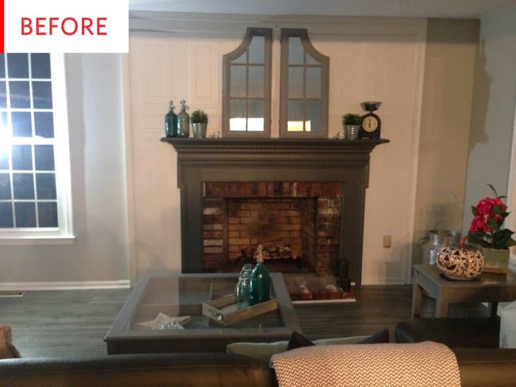 Living room with brick fireplace, dark mantel, decorative bottles, plants, and a glass coffee table.