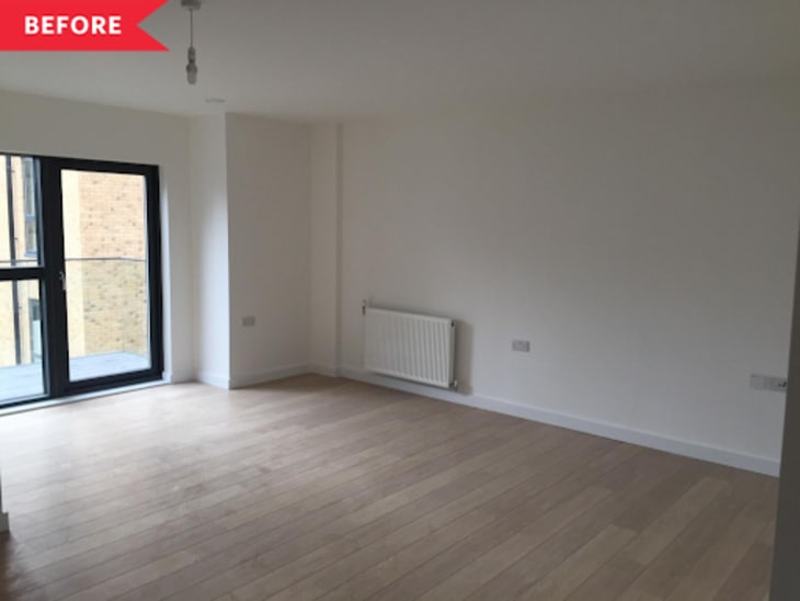 Empty room with light wood flooring, radiator, and large black-framed window.