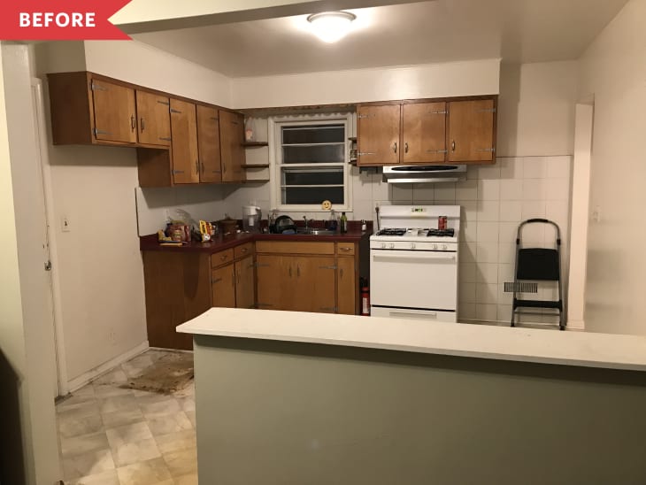 Dated kitchen with wooden cabinets, white stove, red countertops, and a folding chair against tiled wall.