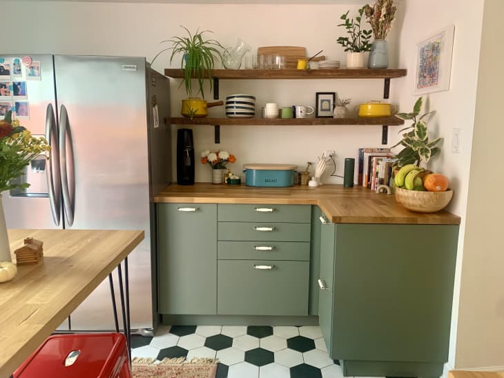 厨房有黑白地板，绿色橱柜和不锈钢冰箱