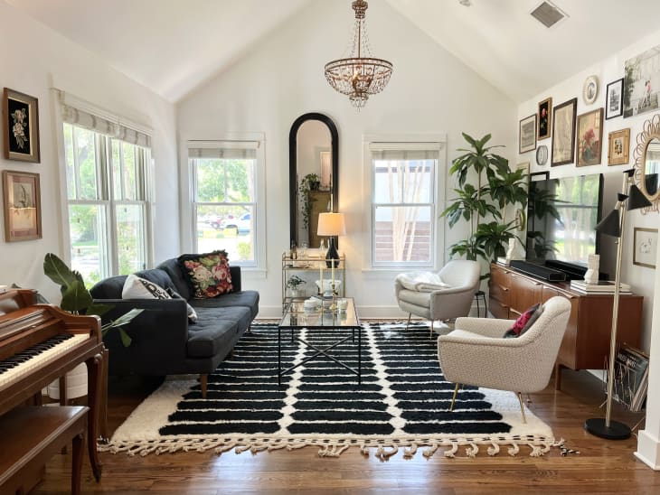 Living room with large black and white area rug with black couch and white lounge chairs. Across from a gallery wall.